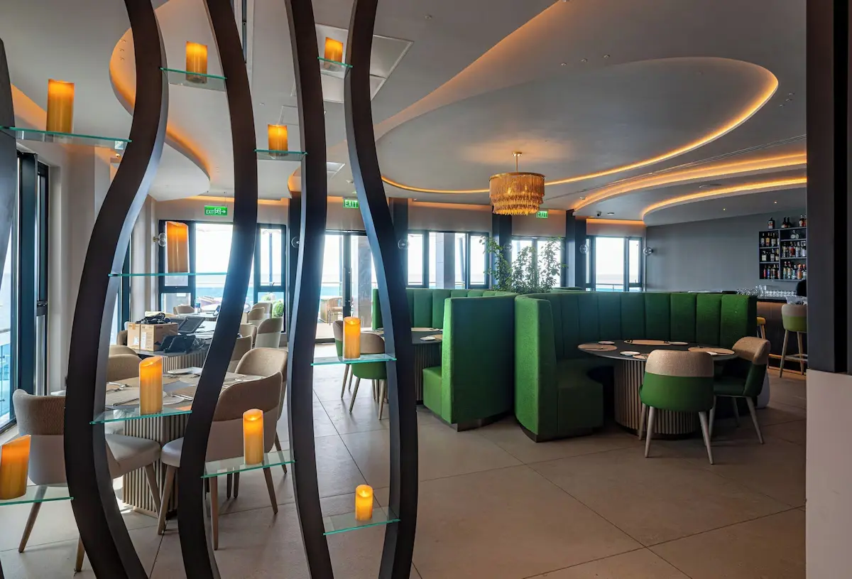 Complete Restaurant Furniture and Lighting - GZS Procurement Interior restaurant view showing dining tables and chairs, the bar area, and unique candle-display shelving, confirming the complete FF&E package from GZS.