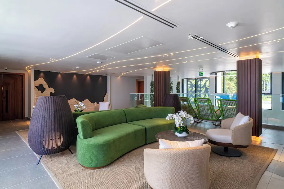Hotel Lounge and Lobby Furnishings - GZS Sourced FF&E Ocean Oasis Hotel common area with modern curved green sofa, armchairs, and floor lamps, demonstrating the diverse FF&E sourced by GZS for public spaces.