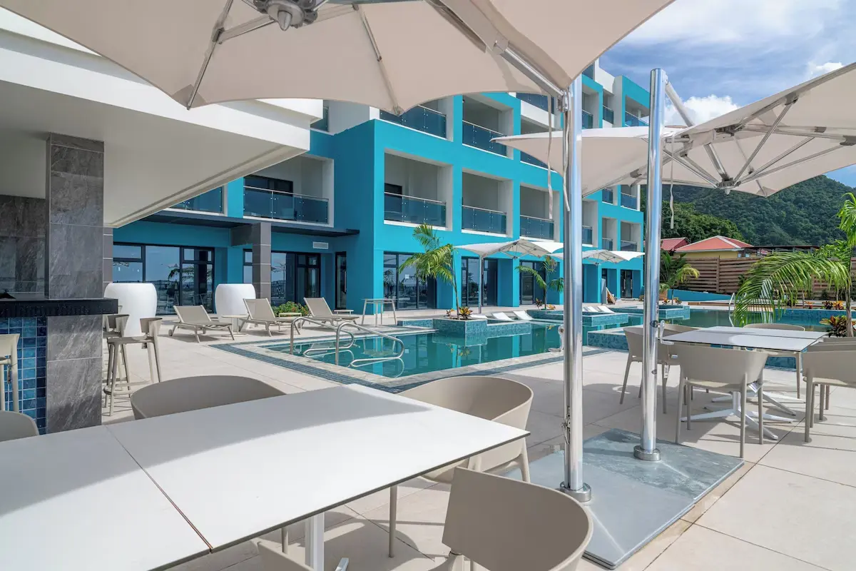 Ocean Oasis Hotel with Tensile Canvas Roof and Contemporary Design Covered outdoor patio and dining area adjacent to the pool, featuring white modern tables and large cantilever umbrellas, showcasing GZS's outdoor FF&E supply.