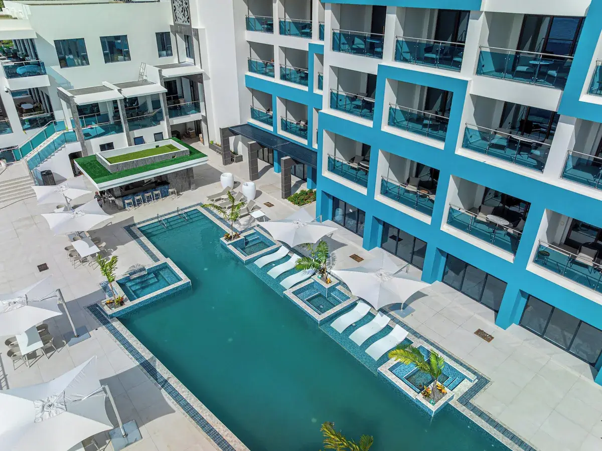 Inner Courtyard Pool Area - GZS Outdoor Equipment Aerial view of the Ocean Oasis Hotel's inner courtyard pool surrounded by turquoise and white buildings, featuring GZS-sourced poolside furniture and umbrellas.