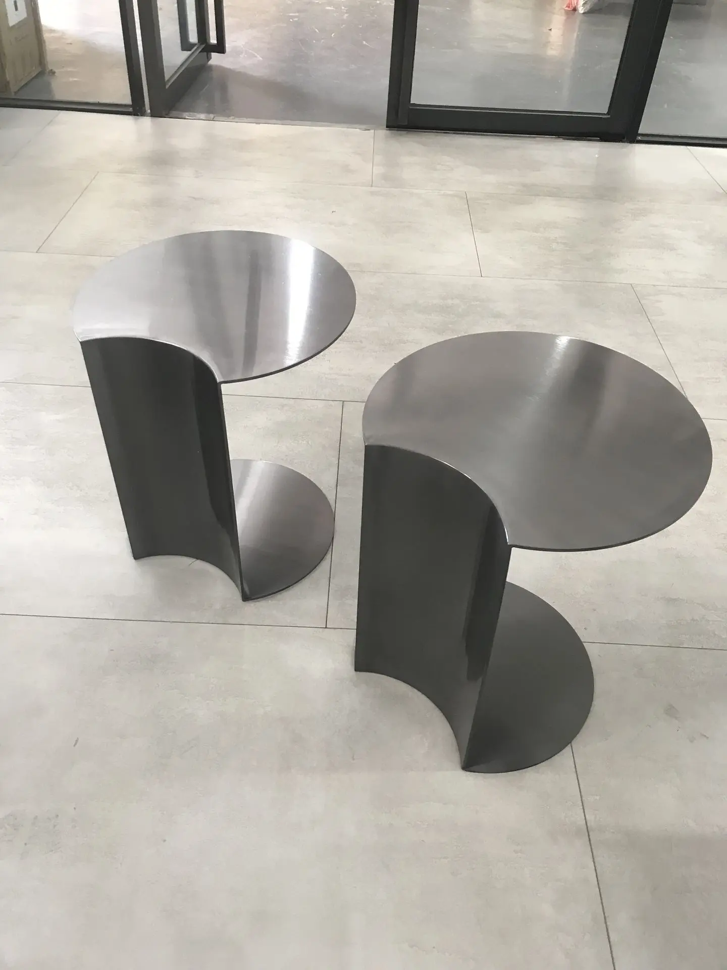 Custom Metal Tables Sourcing: Sculptural Loose Furniture China Pair of contemporary C-shaped metal tables with a dark, polished finish, showcasing sculptural and industrial style loose furniture china suitable for a modern lounge.