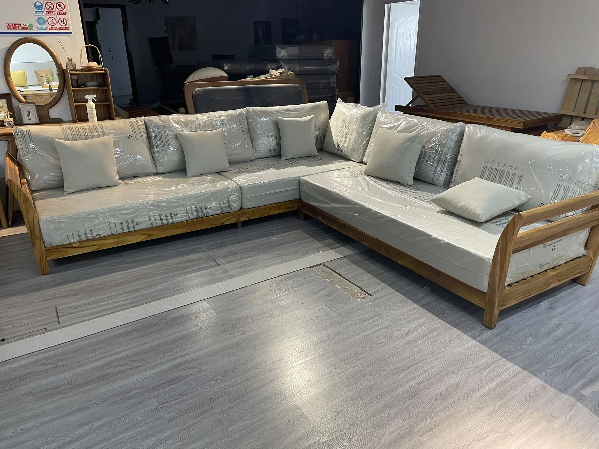 Modular Solid Teak Wood Sectional Sofa: Loose Furniture China Sourcing and Supply L-shaped modular sectional sofa with a natural light wood frame and thick cushions wrapped in plastic, showcasing large-scale residential or contract loose furniture china