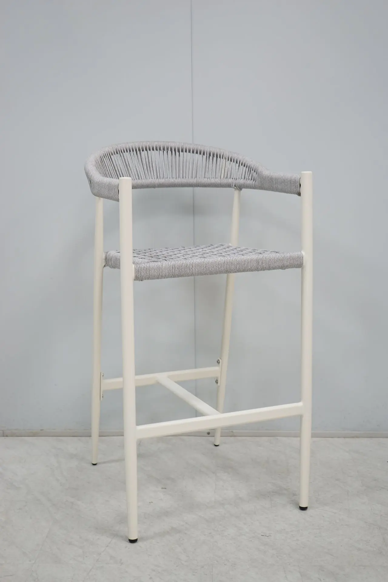 Rattan Chair Style Bar Stool: Loose Furniture China Woven Design Contemporary bar stool featuring a woven gray rope seat and backrest, on a light cream metal frame. This rattan chair-style seating is sourced as loose furniture china for commercial use.