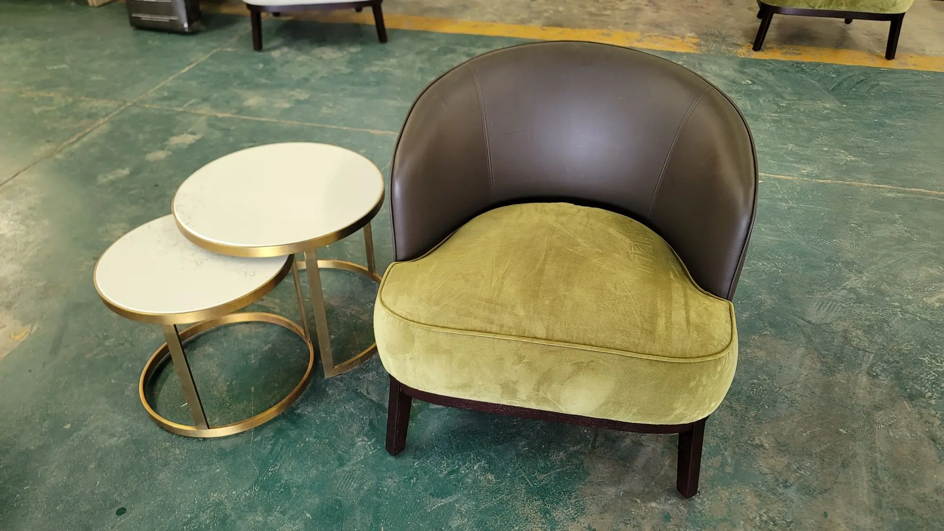 Luxury Hotel Seating: Upholstered Armchair and Side Tables Loose Furniture China Luxury hotel style barrel-back armchair with a brown leather or velvet shell and a plush olive green velvet cushion, next to two nested white marble-top side tables with gold frames, showcasing loose furniture china quality.