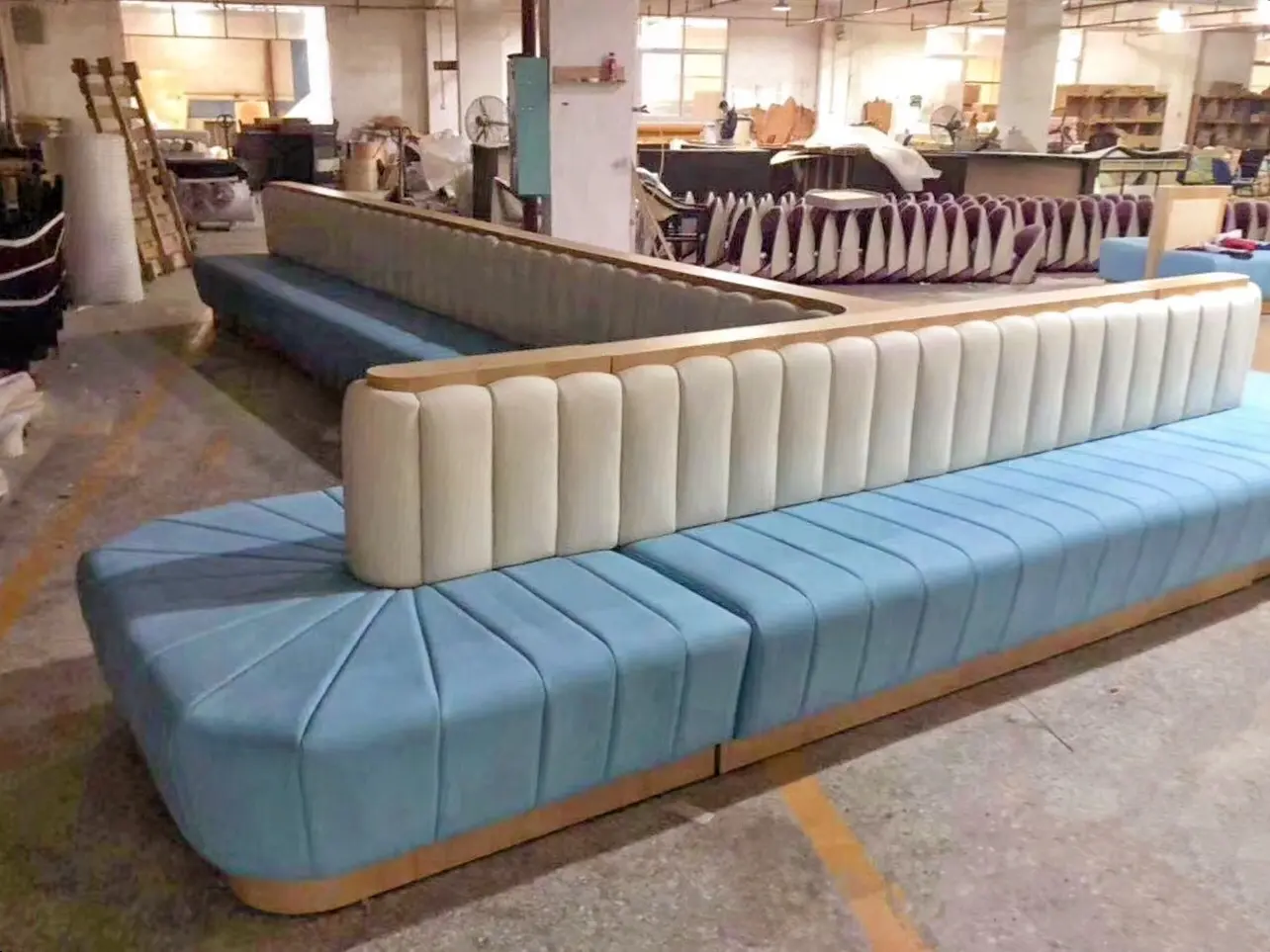 Commercial Banquet Seating: Custom Modular Sofa Loose Furniture China Custom modular banquet seating, upholstered in light blue and cream channel tufting with a light wood base, displayed on a factory floor, ready for use as commercial loose furniture china.