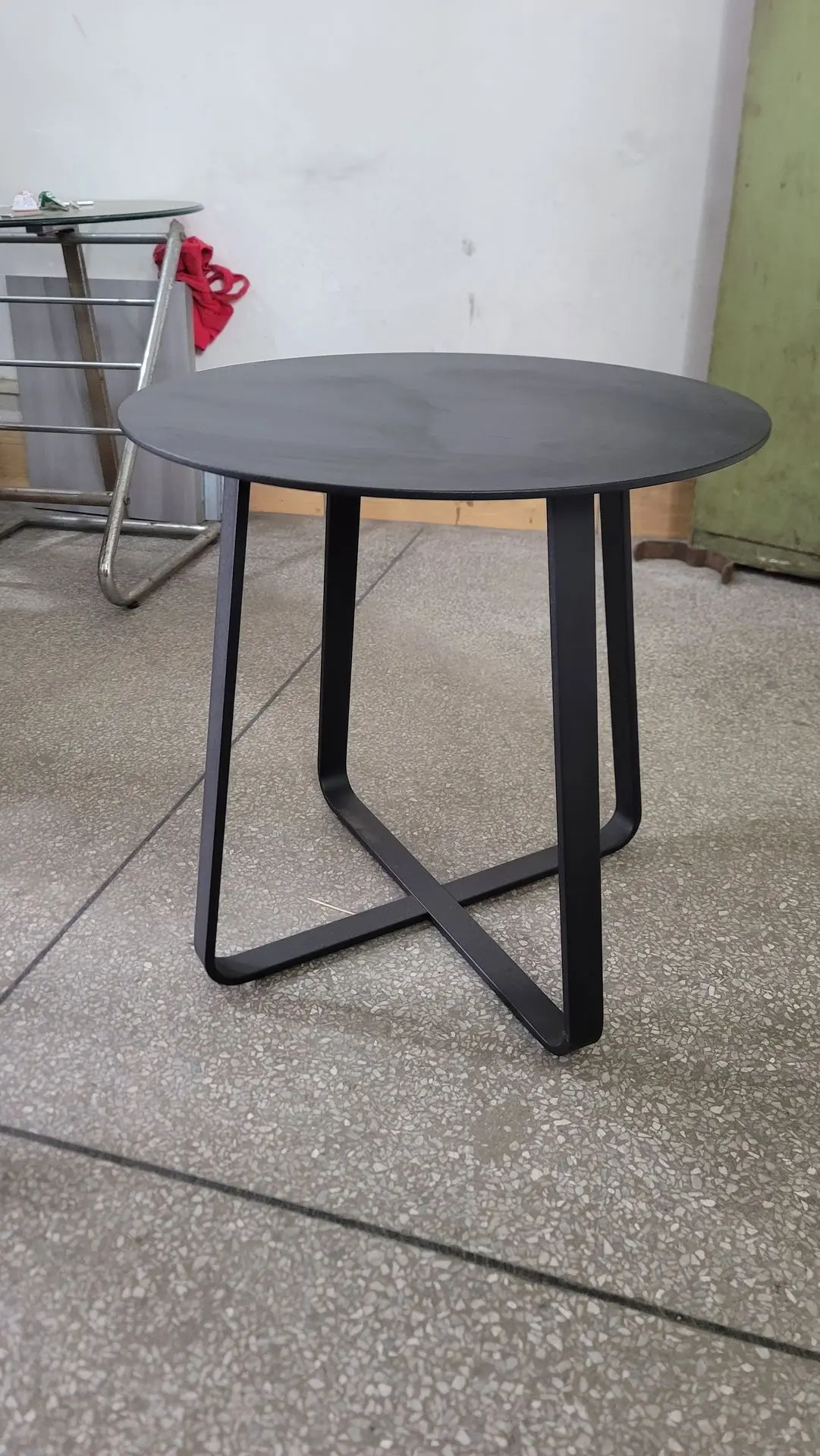 Black Metal Side Table: Minimalist Loose Furniture China Sourcing Minimalist round black metal side table featuring a curved X-shaped base, showcasing compact and durable loose furniture china suitable for cafe or lounge use.