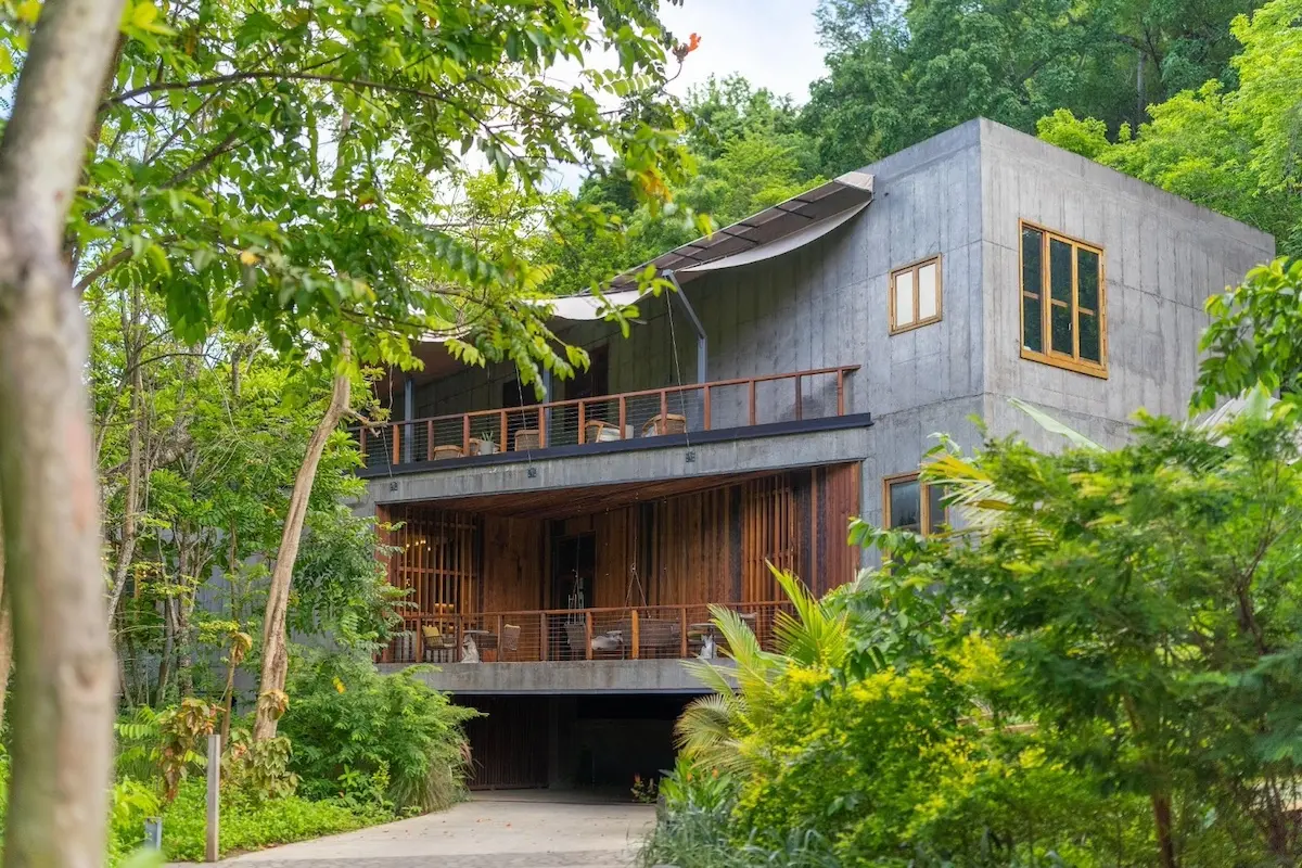 Modern concrete and wood art barn at Secret Bay Dominica surrounded by lush greenery, featuring stairs, lighting, joinery, and furniture sourced by Guangzhou Sourcing.