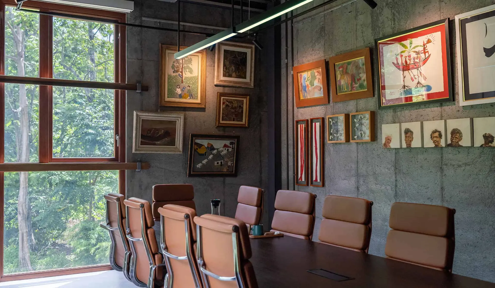 Secret Bay Conference Room with Art-Filled Interior Design Conference room at Secret Bay featuring leather chairs, large wooden table, and curated art displayed on concrete walls with forest views.