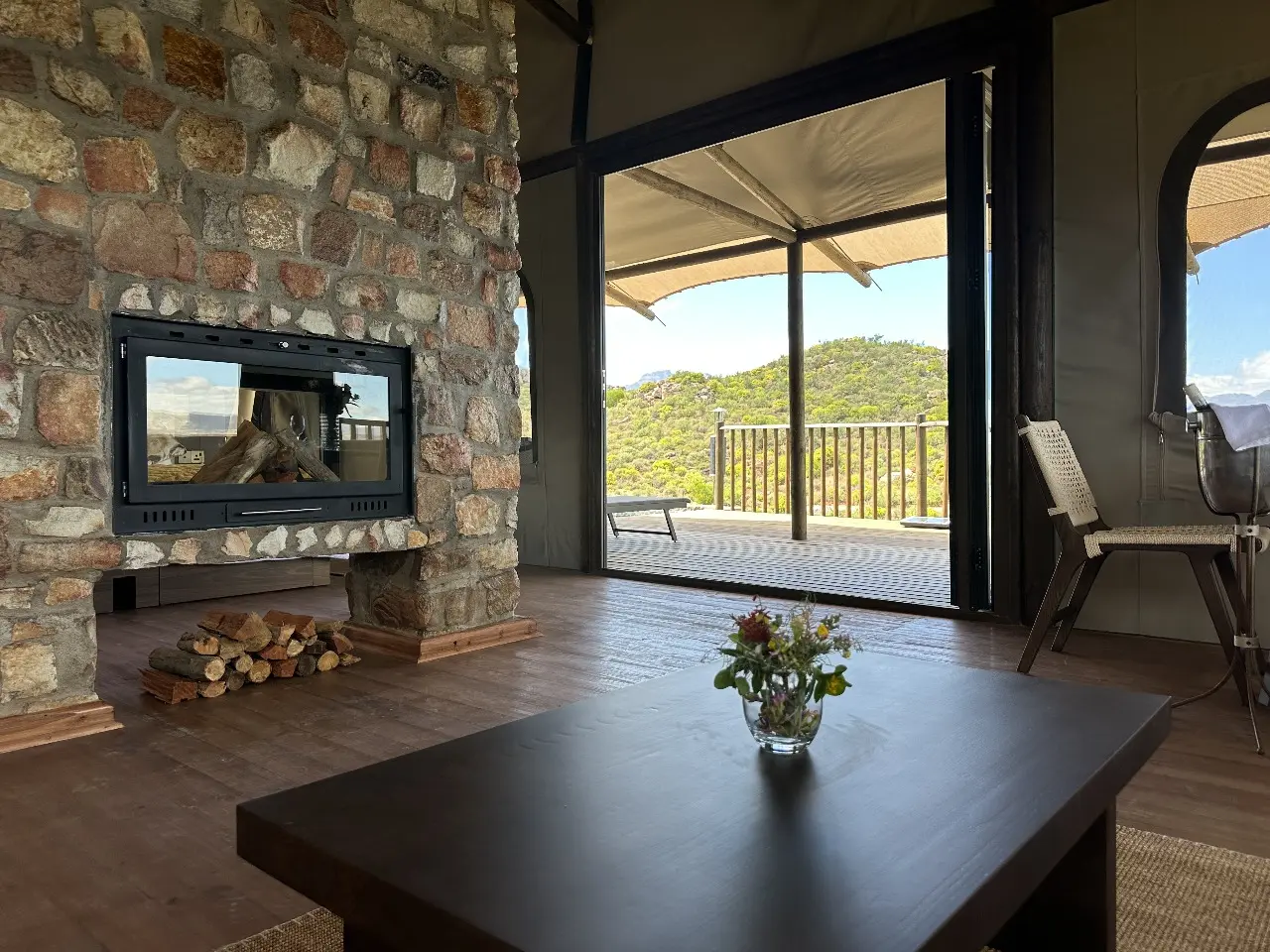 Luxury Yamu villa interior featuring stone fireplace, hardwood flooring, tensile canvas roof, and furnished living space overlooking the natural landscape.