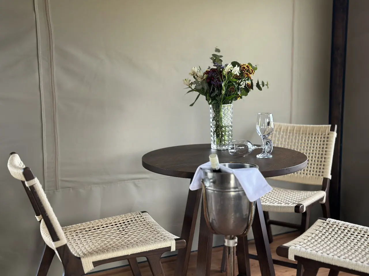 Yamu tent suite living and dining area with woven chairs, pendant lighting, and natural light views.