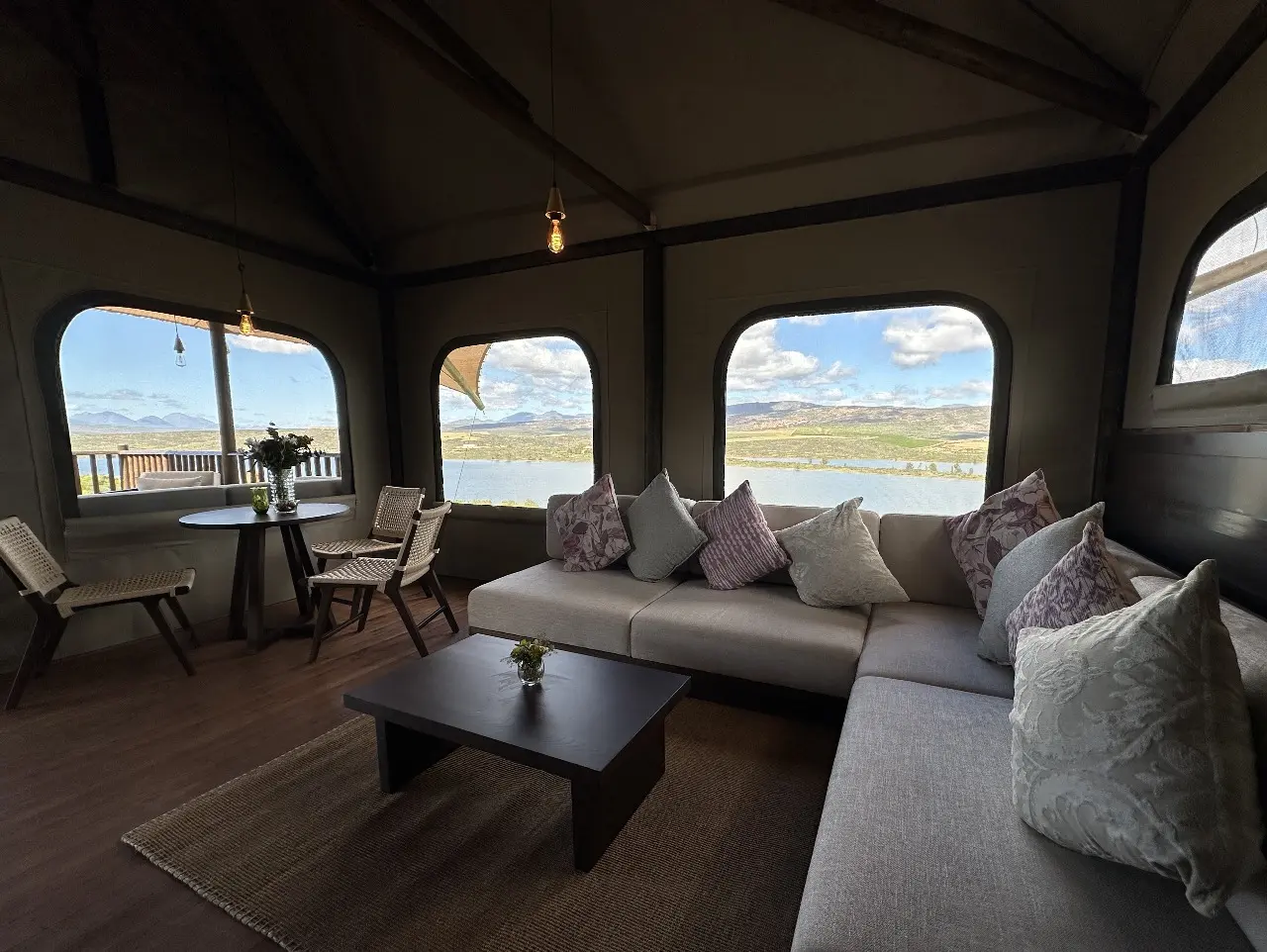 Yamu tent suite lounge with sectional sofa, accent pillows, and sweeping mountain and lake views.