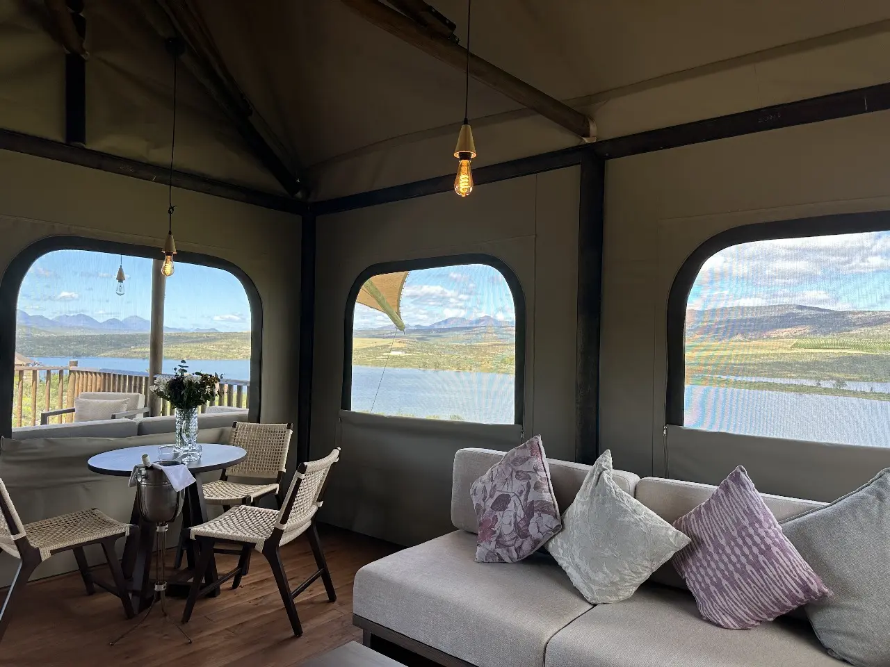 Yamu tent suite dining and seating area with large windows and scenic outdoor landscape.