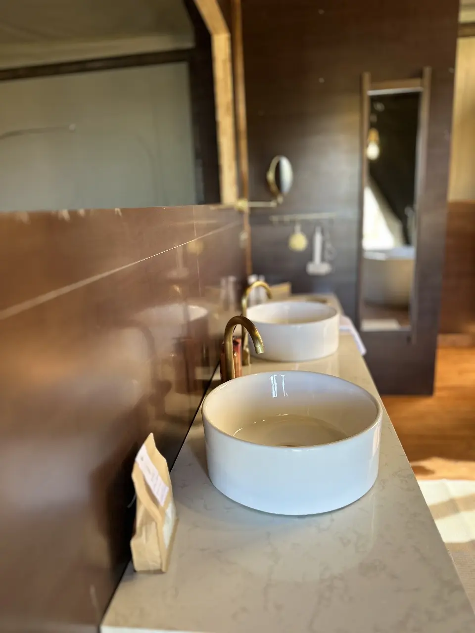 Yamu tent suite bathroom featuring double ceramic basins, brass fixtures, and marble countertop.