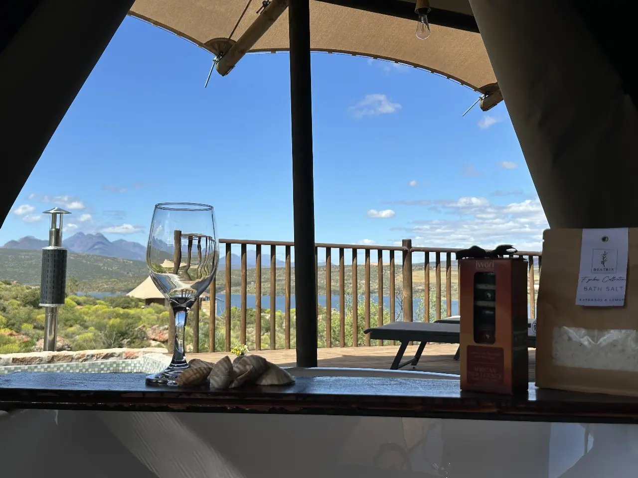 Yamu tent suite bathtub with tray, wine glasses, and panoramic outdoor views.