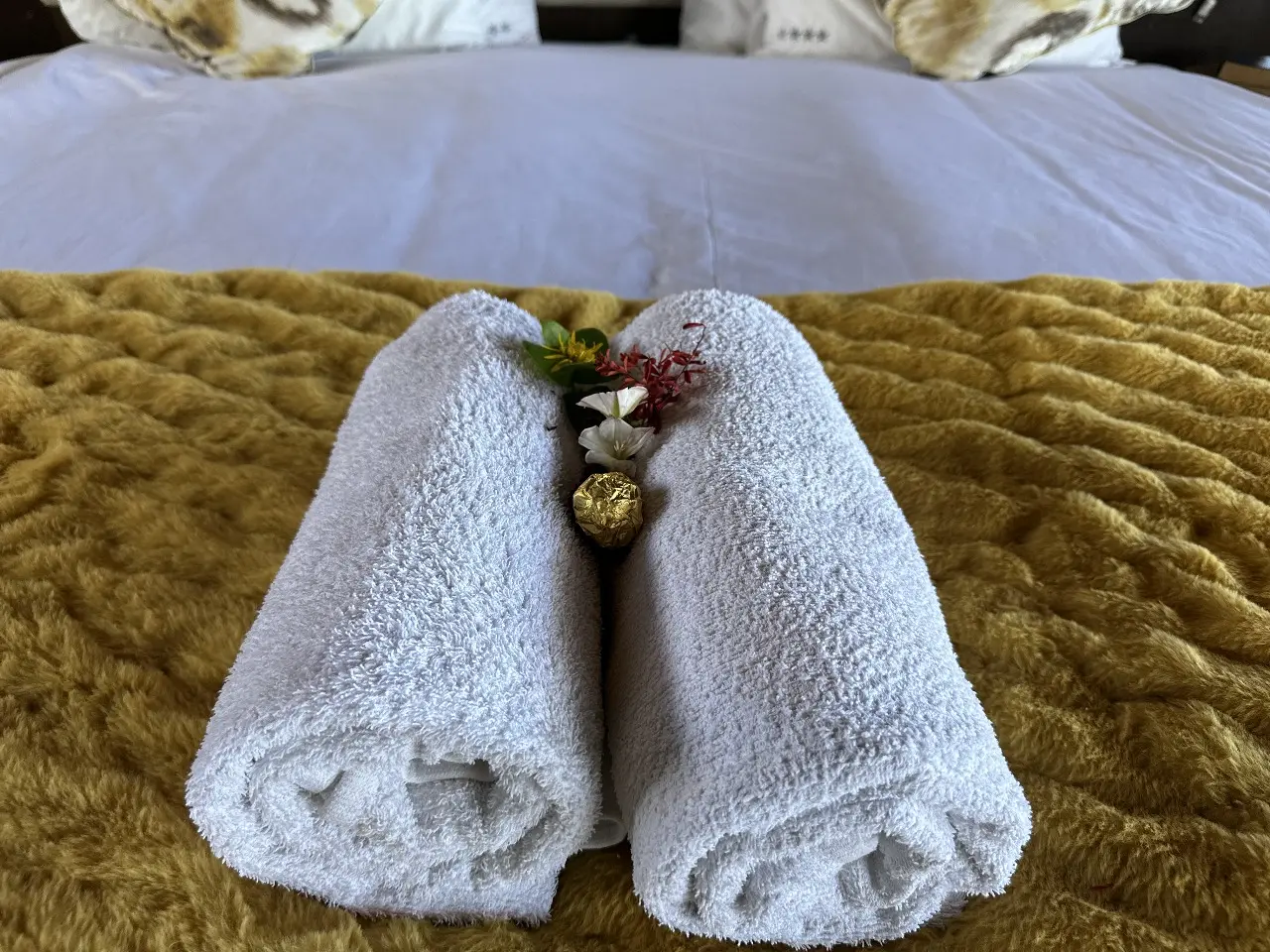 Fresh rolled towels and decorative accents placed on bed in Yamu tent suite.