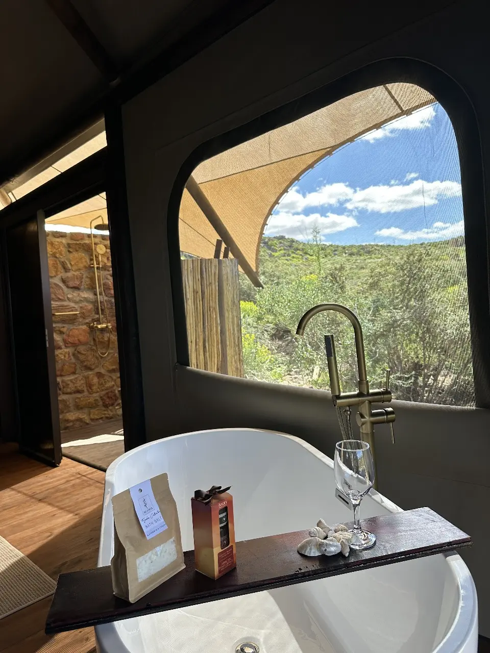 Freestanding bathtub in Yamu tent suite overlooking mountain landscape through large canvas