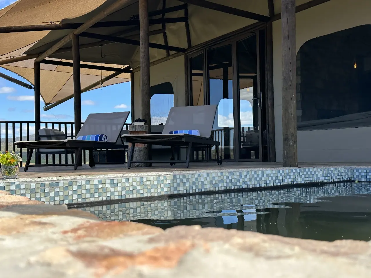 Yamu poolside area featuring cushioned loungers, wooden decking, and tensile canopy shade.