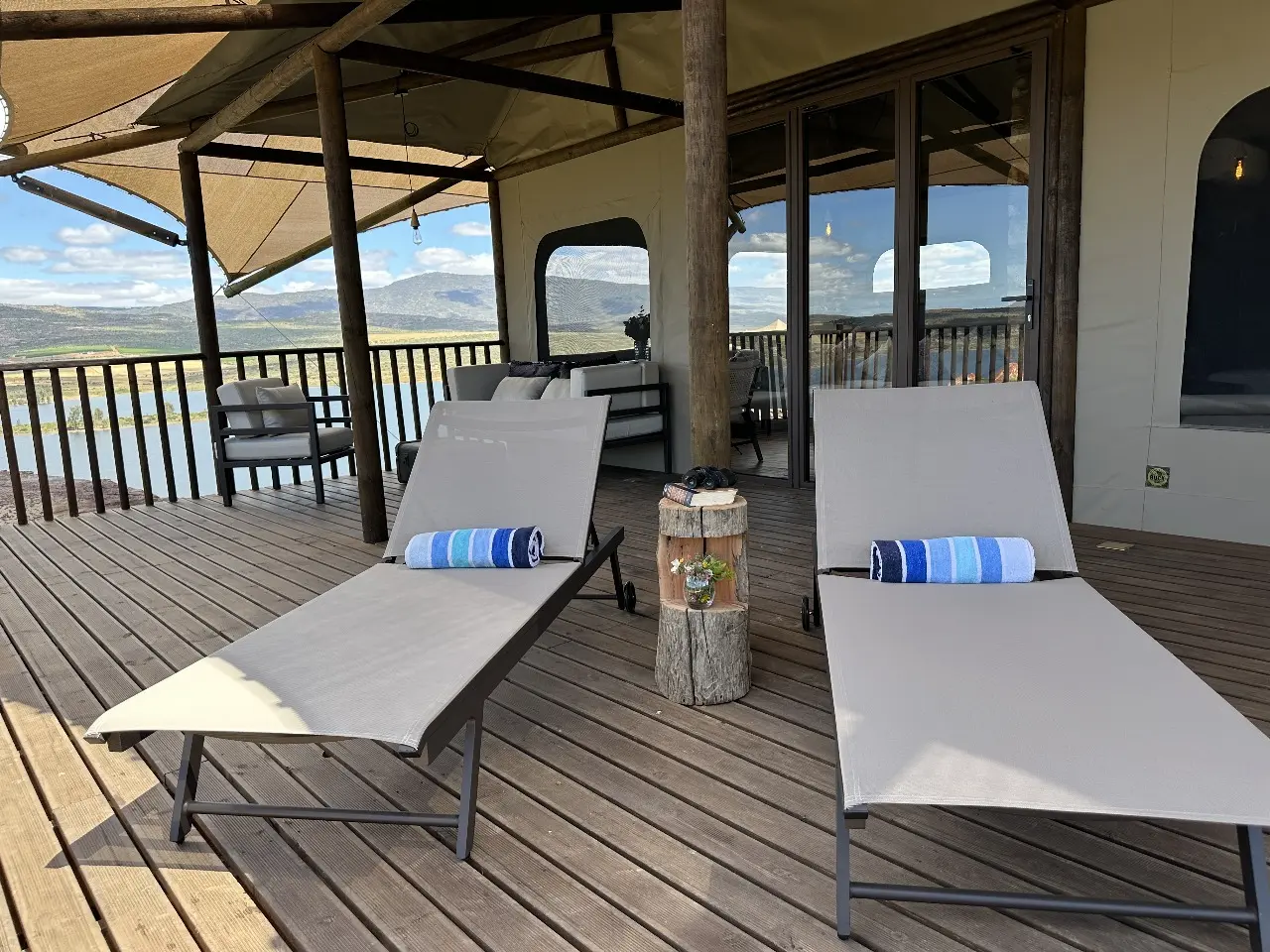 Pair of cushioned loungers with rustic wood stump table on Yamu’s elevated outdoor deck.