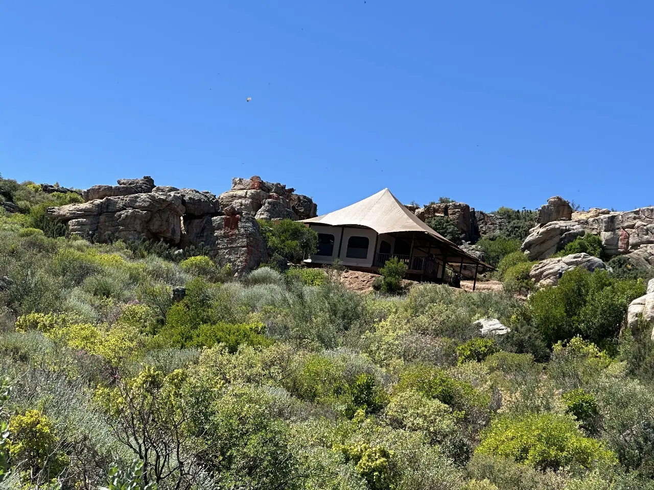 GZS sourced safari-style Yamu tent villa with tensile canvas roof among rocky terrain.