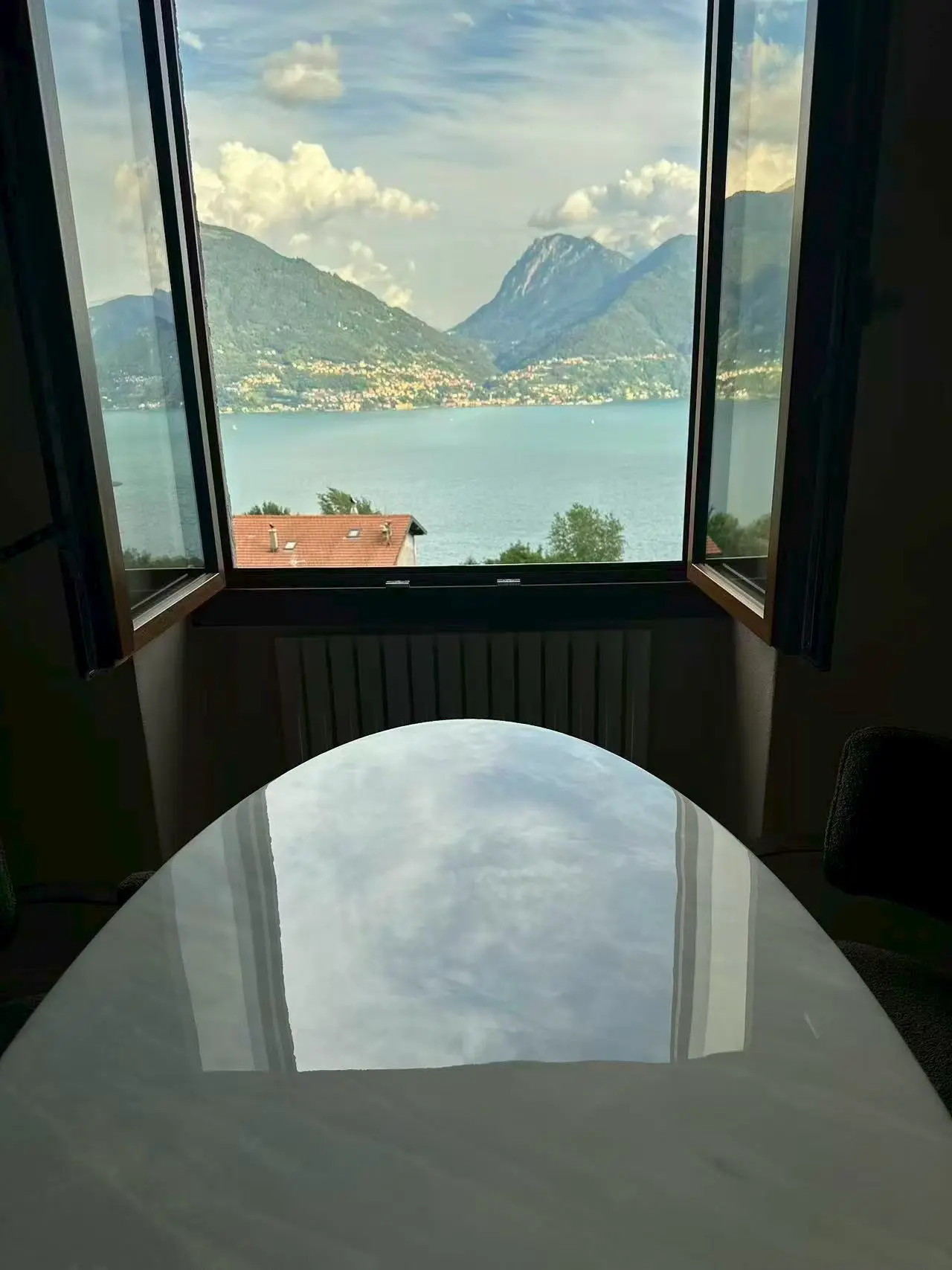 GZS sourced marble-top dining table at Lake Como Boutique Hotel with an open window overlooking the lake and mountains.