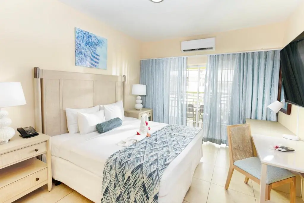 Refurbished Bay Garden Hotel guest room featuring GZS sourced SPC flooring, loose furniture, artwork, drapery, and upgraded lighting for a modern, inviting atmosphere.