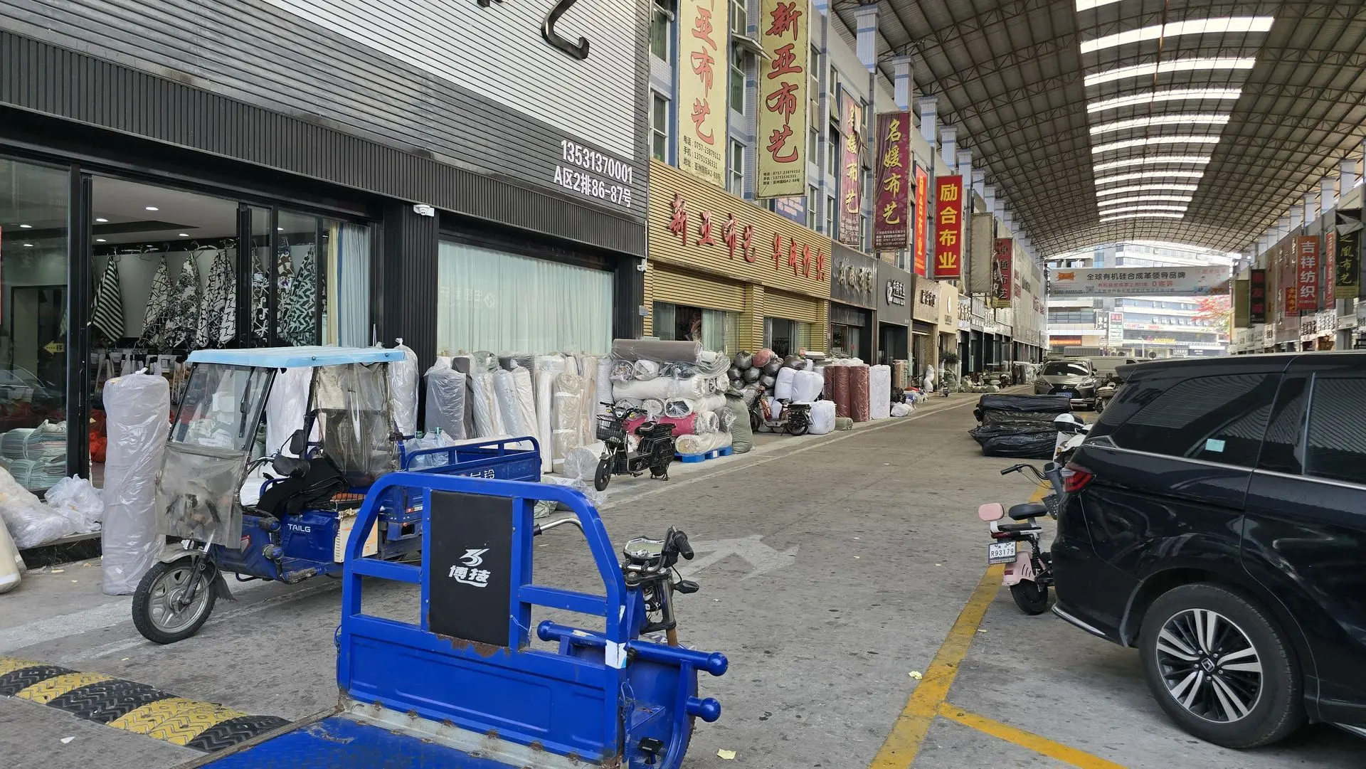 Fabric and textile shops in a Chinese wholesale market with building materials displayed outside