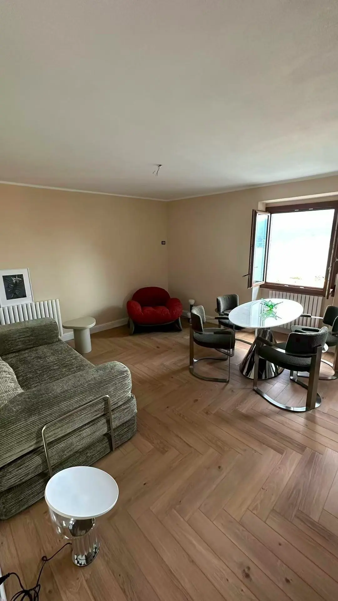Living area with green sofa, red accent chair, and glass dining set curated by Guangzhou Sourcing for the Lake Como Boutique Hotel.