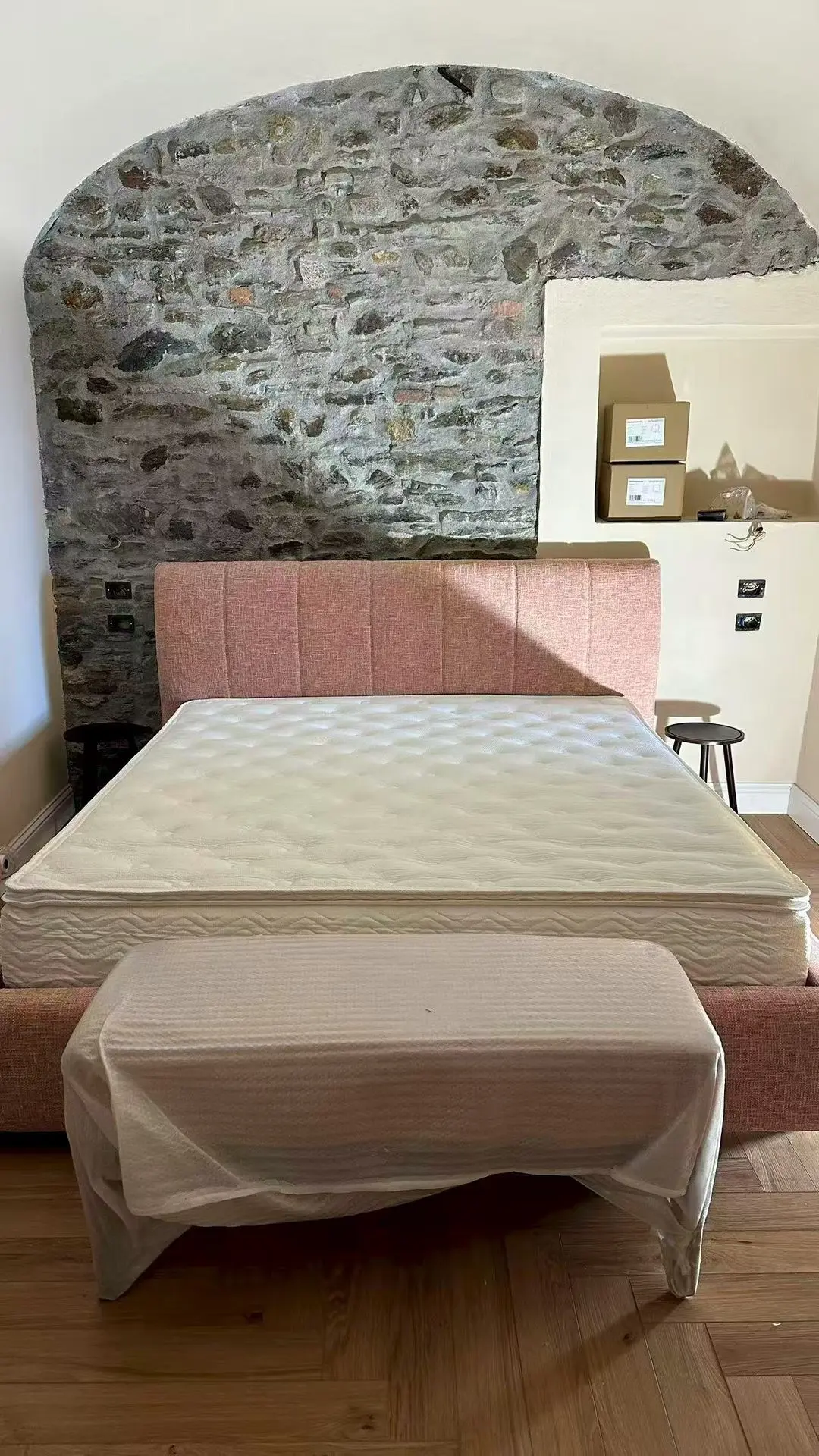 Lake Como Boutique Hotel room featuring a pink upholstered bed against a stone accent wall, sourced and curated by Guangzhou Sourcing.