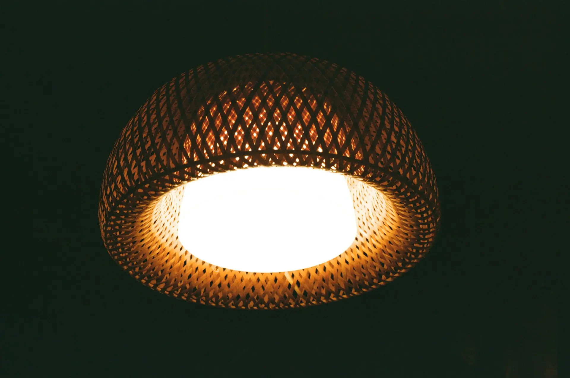 Warm rattan pendant light with woven texture hanging indoors, showcasing natural lighting style for interior design.