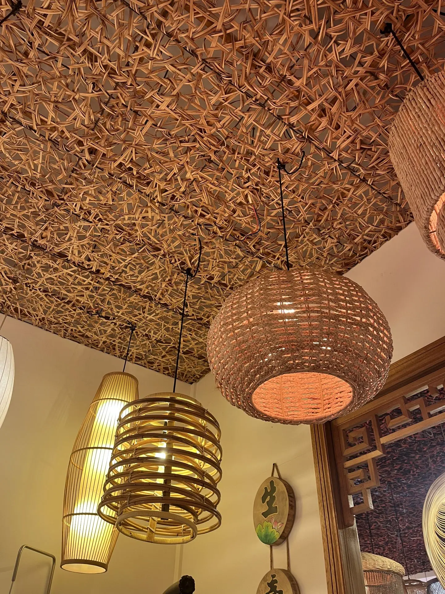 Rattan pendant lights and bamboo lamps displayed in a decorative showroom, featuring woven and spiral designs.