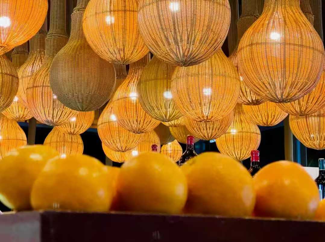 Warm-lit rattan pendant lights in a clustered ceiling display, showcasing handcrafted natural lighting sourced from China