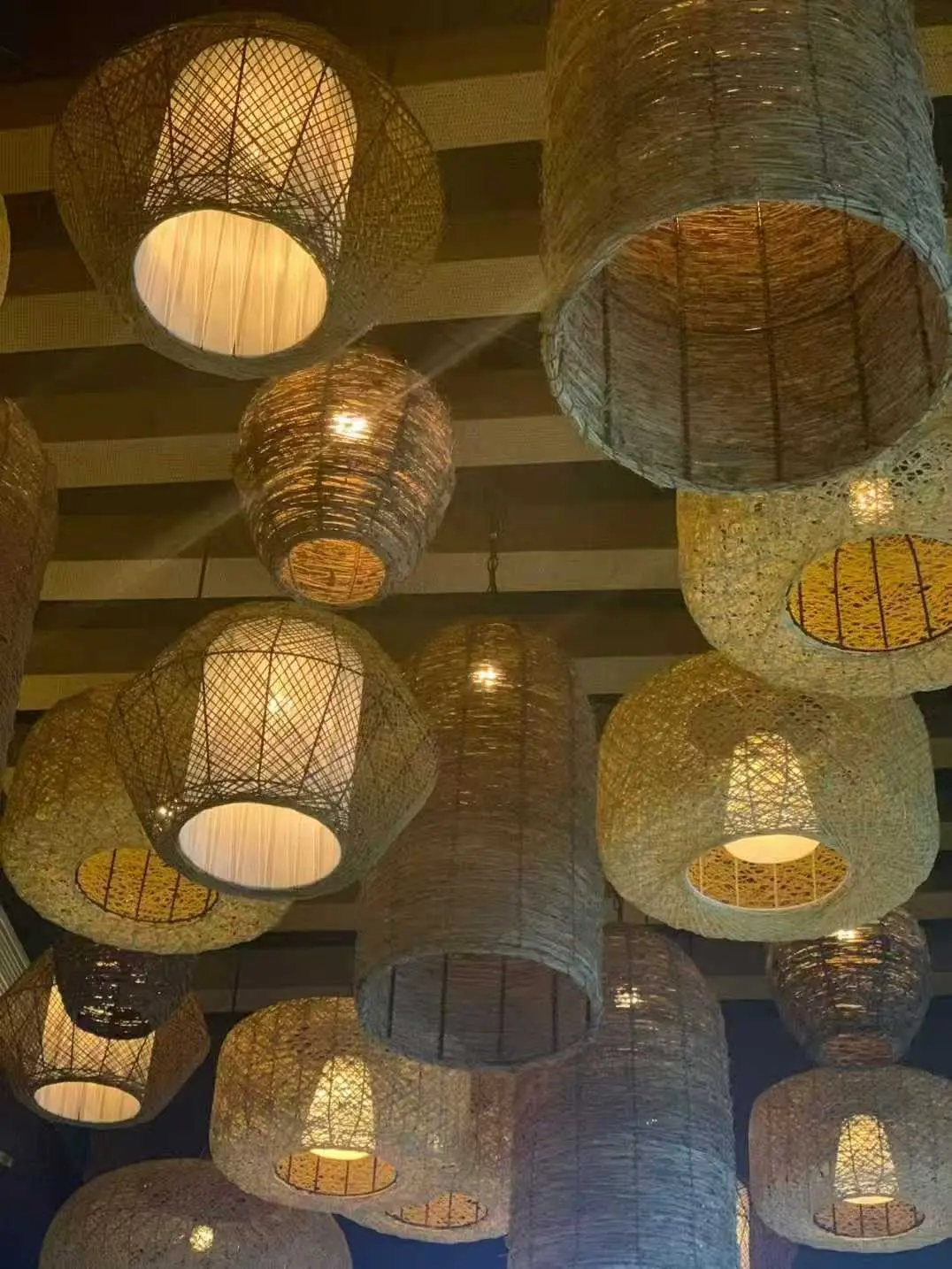 Collection of handwoven rattan pendant lights suspended from ceiling, highlighting natural lighting designs sourced from China
