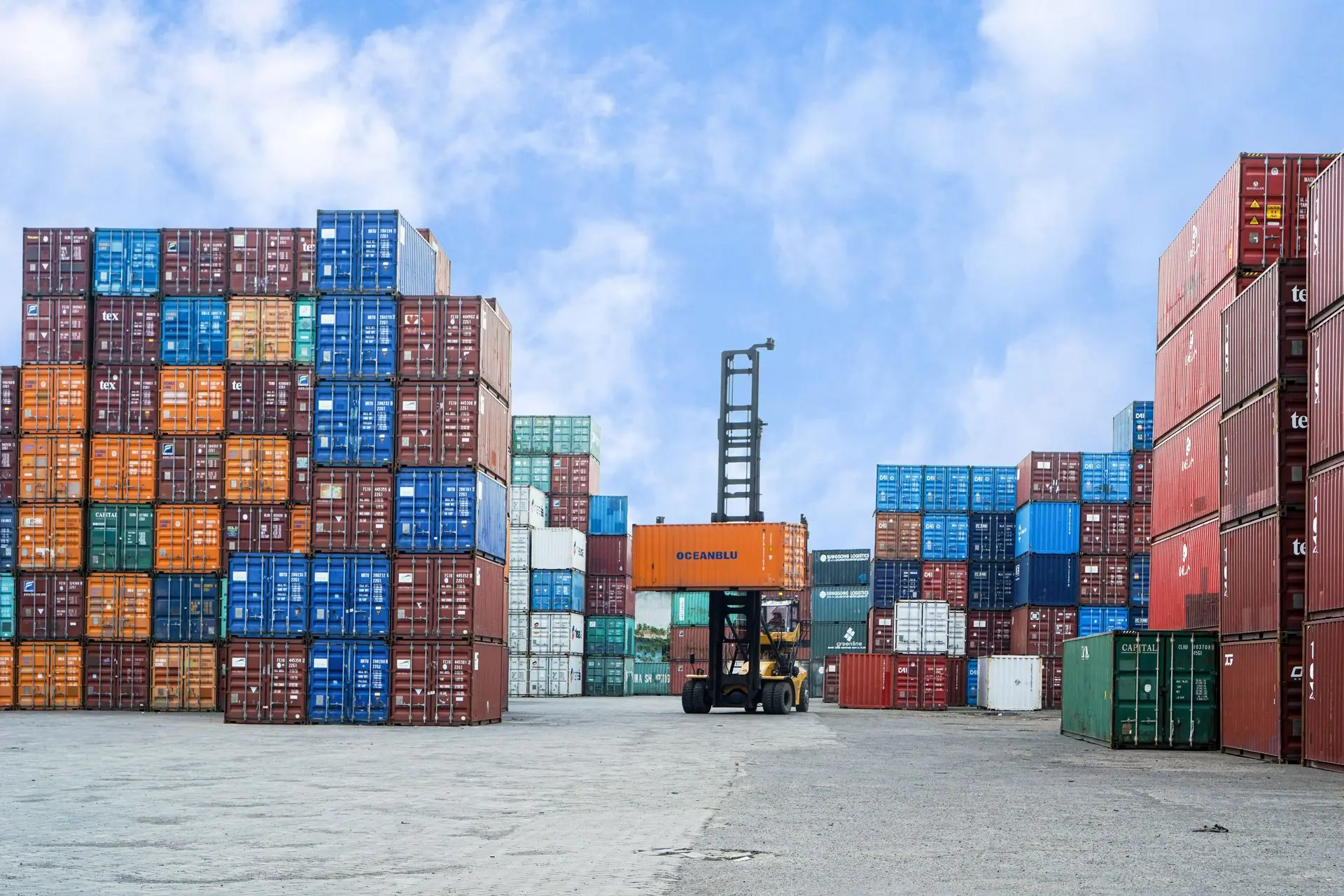 Stacked shipping containers at a Chinese port yard with forklift handling cargo