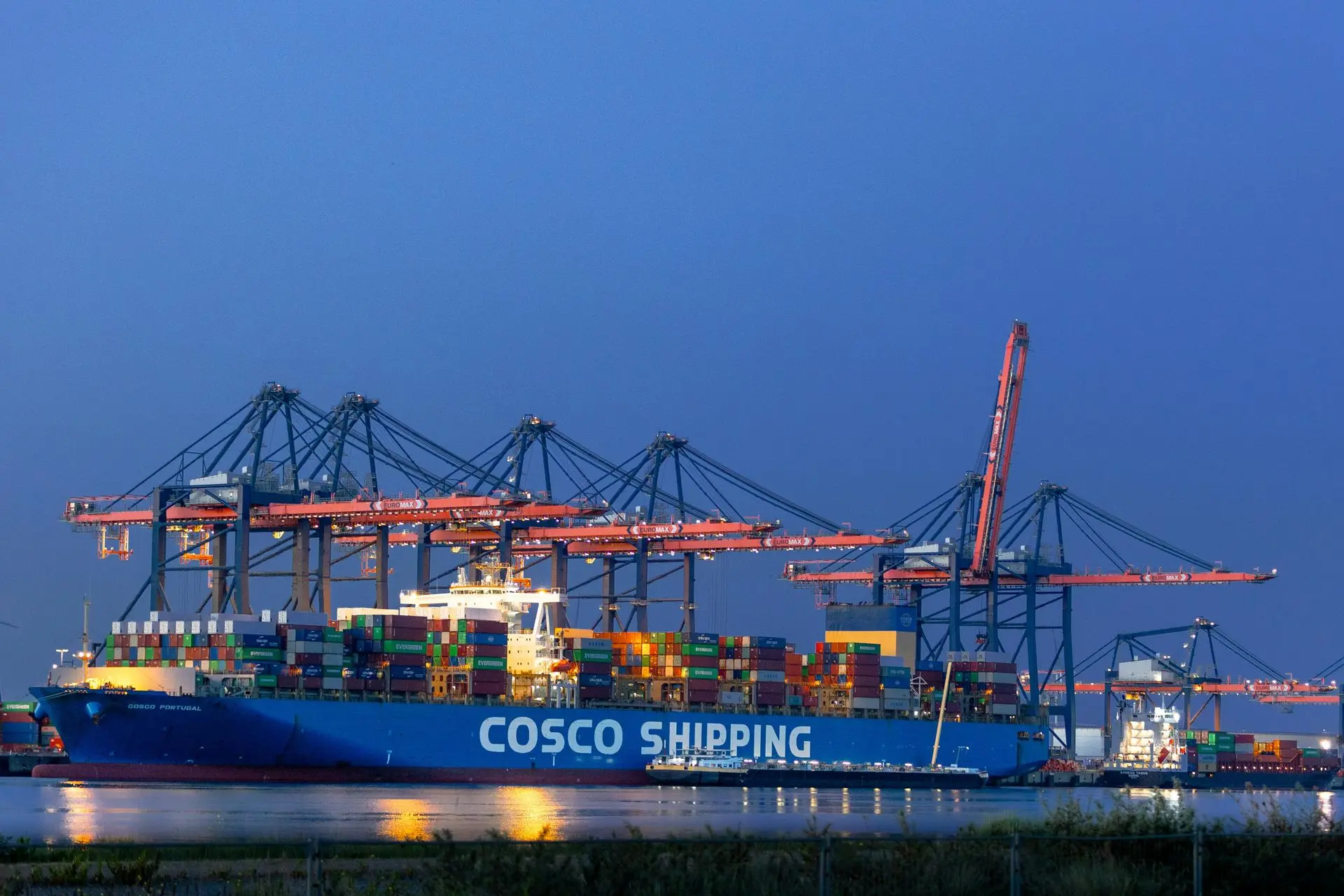 OSCO container ship docked at a major Chinese port with gantry cranes at night