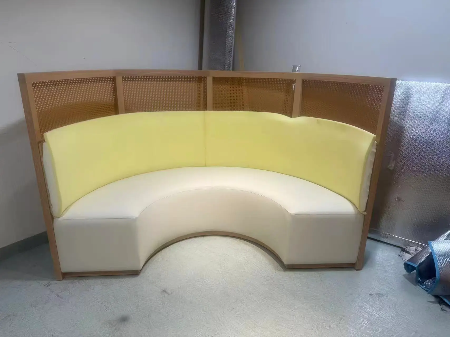 Curved upholstered banquette seating with timber frame and cane backrest, custom-made for hospitality interiors by Guangzhou Sourcing