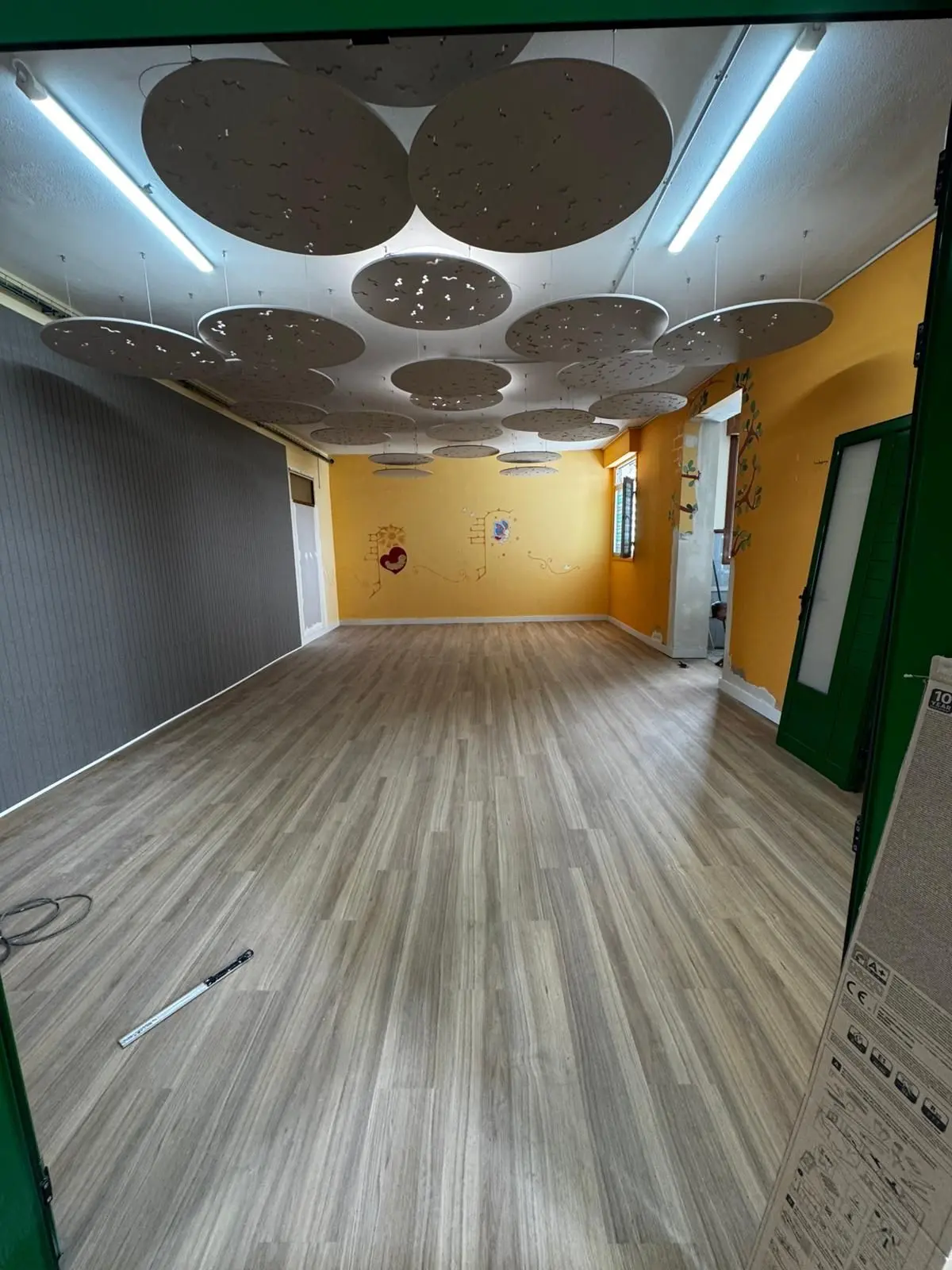 A vibrant installation of circular acoustic ceiling clouds in green, red, orange, and yellow suspended at varying heights for modern noise control.