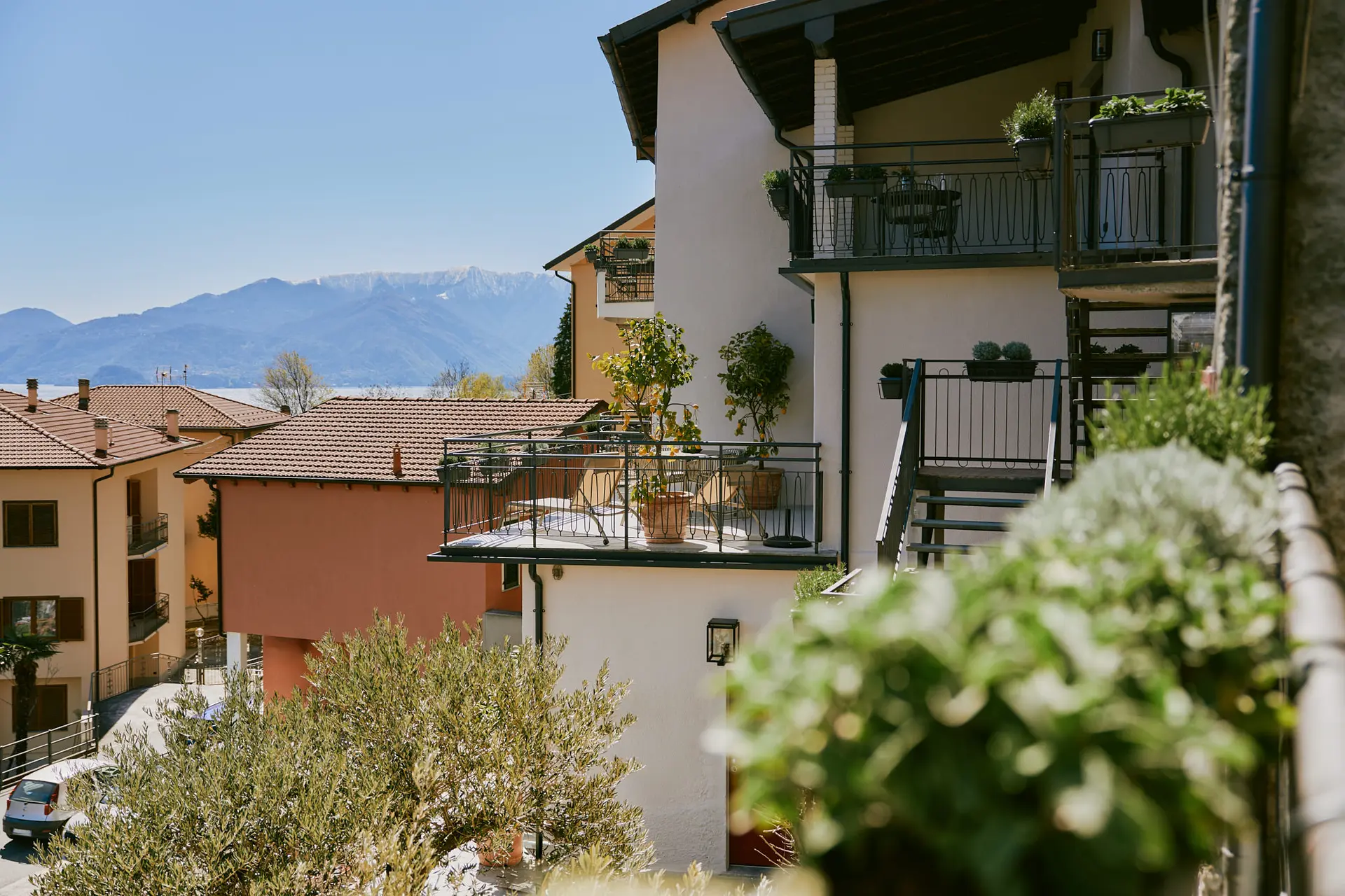 Boutique hotel balcony overlooking Lake Como with sourced outdoor furniture, modern hospitality finishes, and mountain views