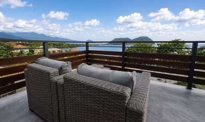 Crystal View outdoor living area with woven lounge furniture, panoramic Caribbean views, and modern balcony railing in Dominica