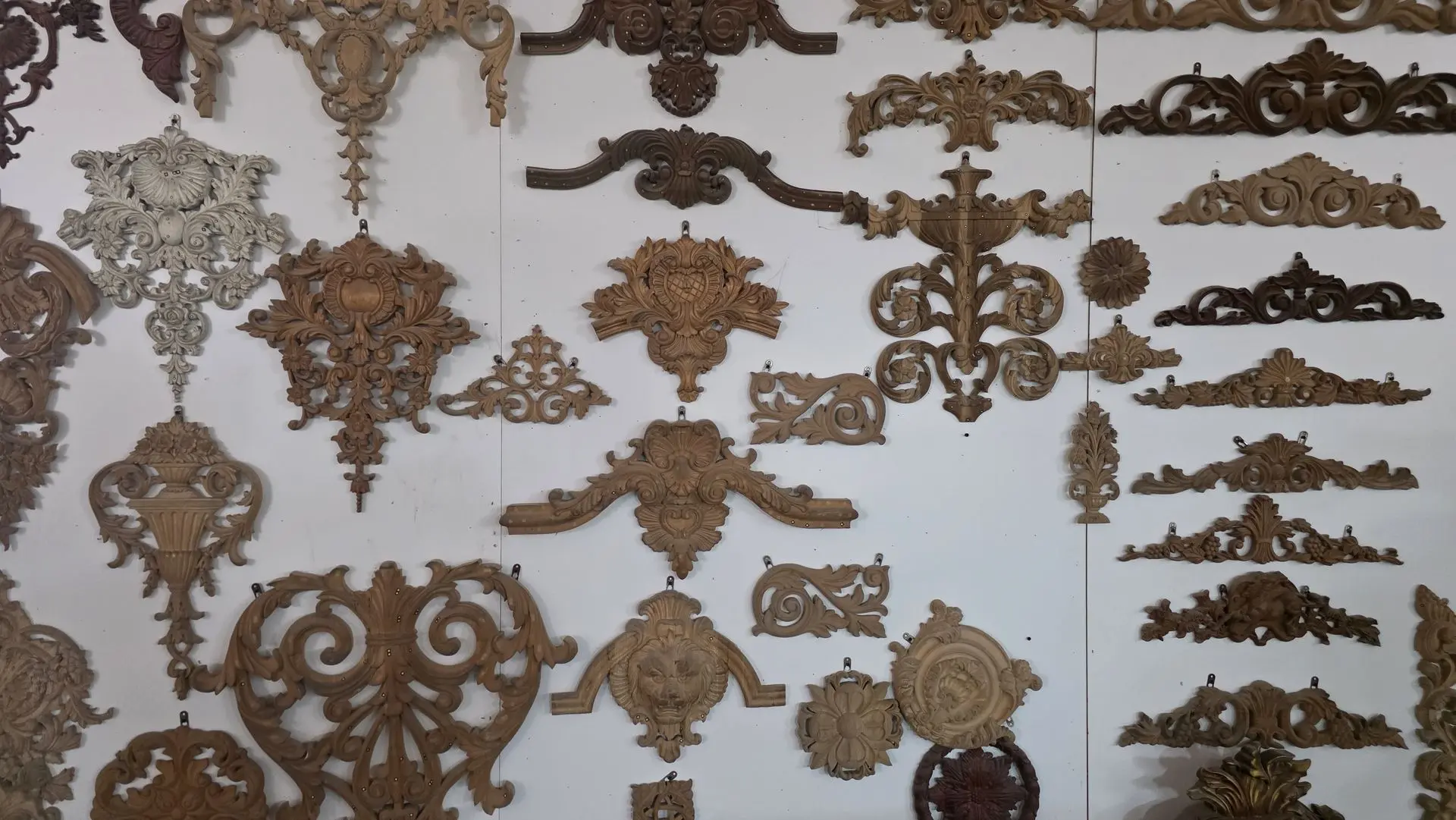 Decorative Wood Carving Designs for Furniture and Architectural Applications Decorative wood carving ornaments and architectural carvings displayed in a manufacturer showroom