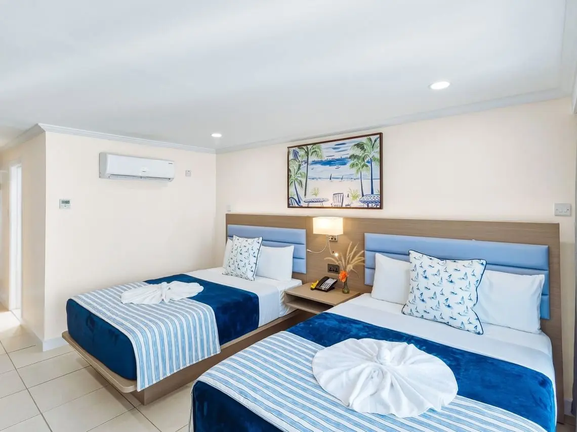 Bay Gardens Marina Haven guest room with twin beds, blue bedding and custom hotel furniture