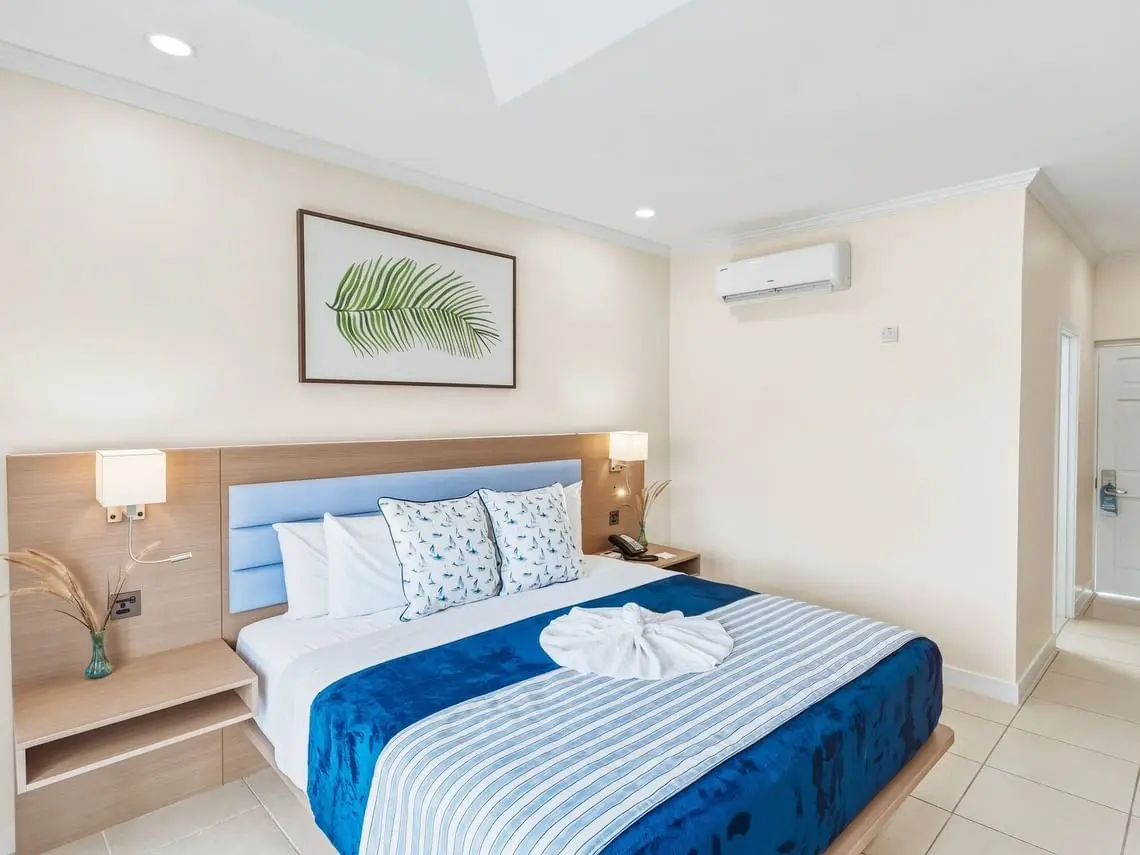 Bay Gardens Marina Haven guest room with king bed, blue bedding and modern hotel furniture