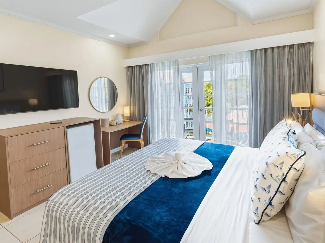 Bay Gardens Marina Haven guest room with king bed, TV console, wardrobe and modern furnishings
