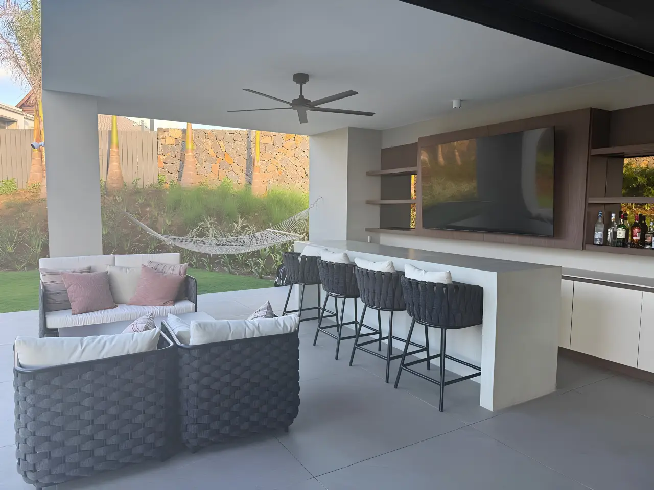 Residential villa outdoor living area in Mauritius with lounge seating, bar counter and covered terrace