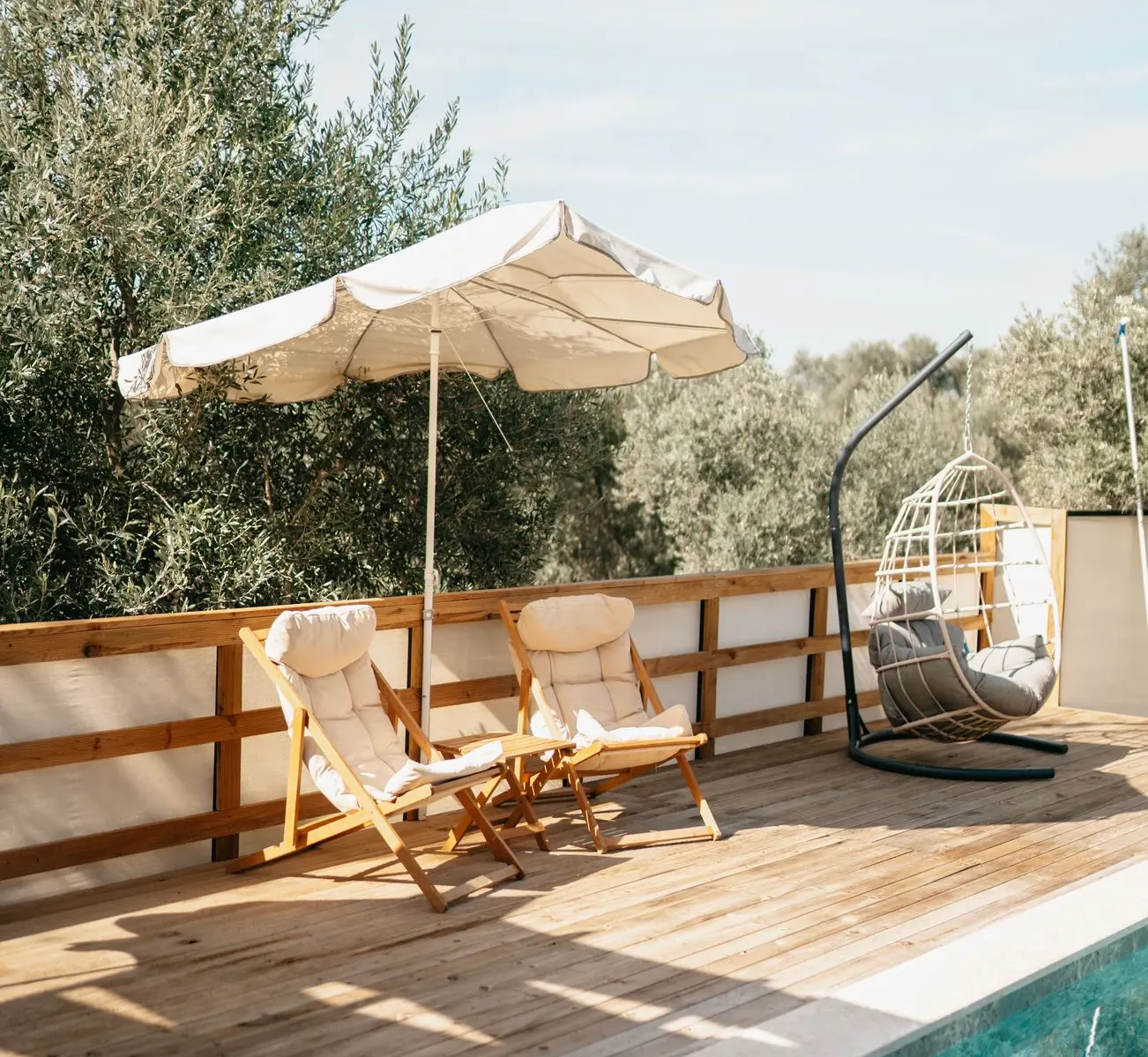 China Patio Furniture for Poolside and Outdoor Lounge Areas China patio furniture with outdoor lounge chairs and hanging chair beside a swimming pool