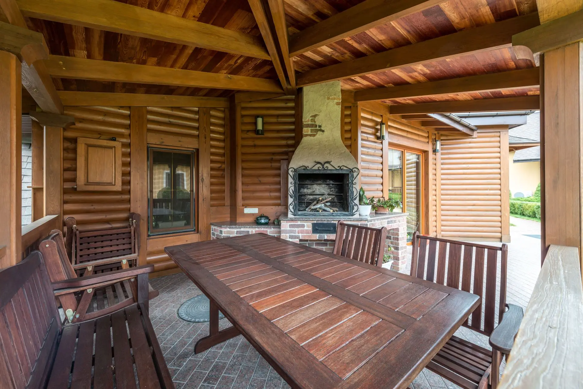 Teak and Wood Patio Furniture for Outdoor Spaces Wood patio dining table and chairs in a covered outdoor space