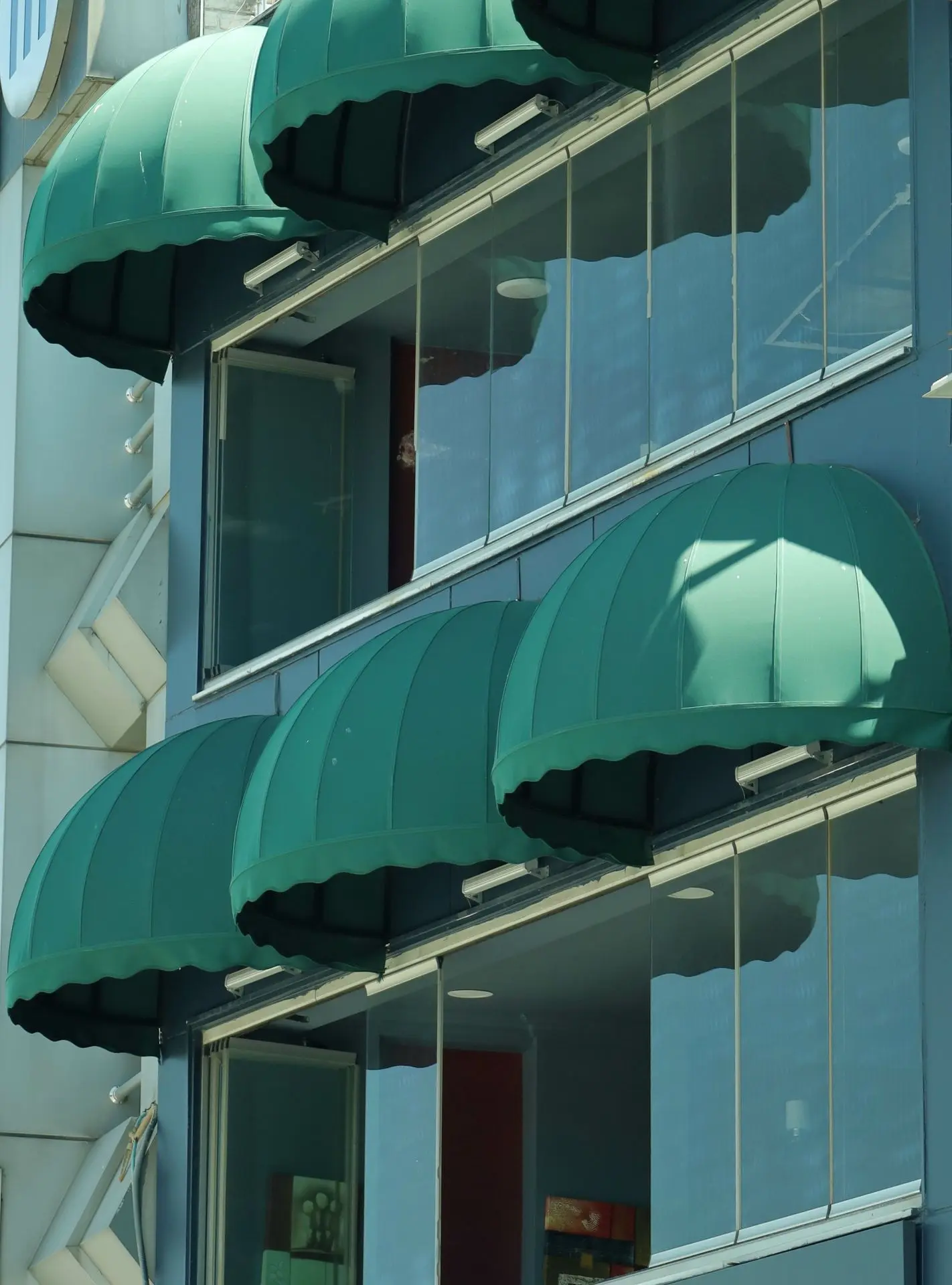 Green fabric awnings providing shade over building windows