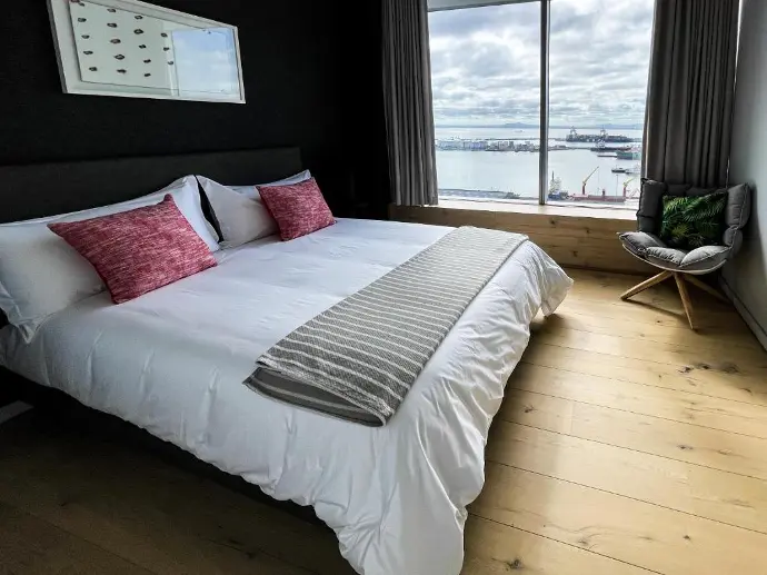 Serene bedroom setting with white sheets and pink pillows on a bed positioned in front of a window.